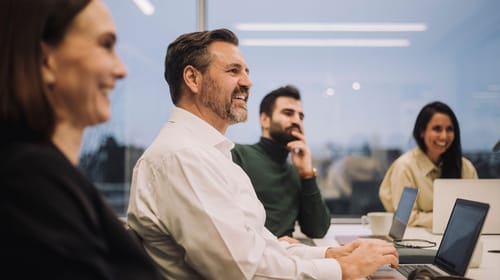 Un groupe de collègues est assis dans une salle et travaille ensemble sur leurs ordinateurs portables