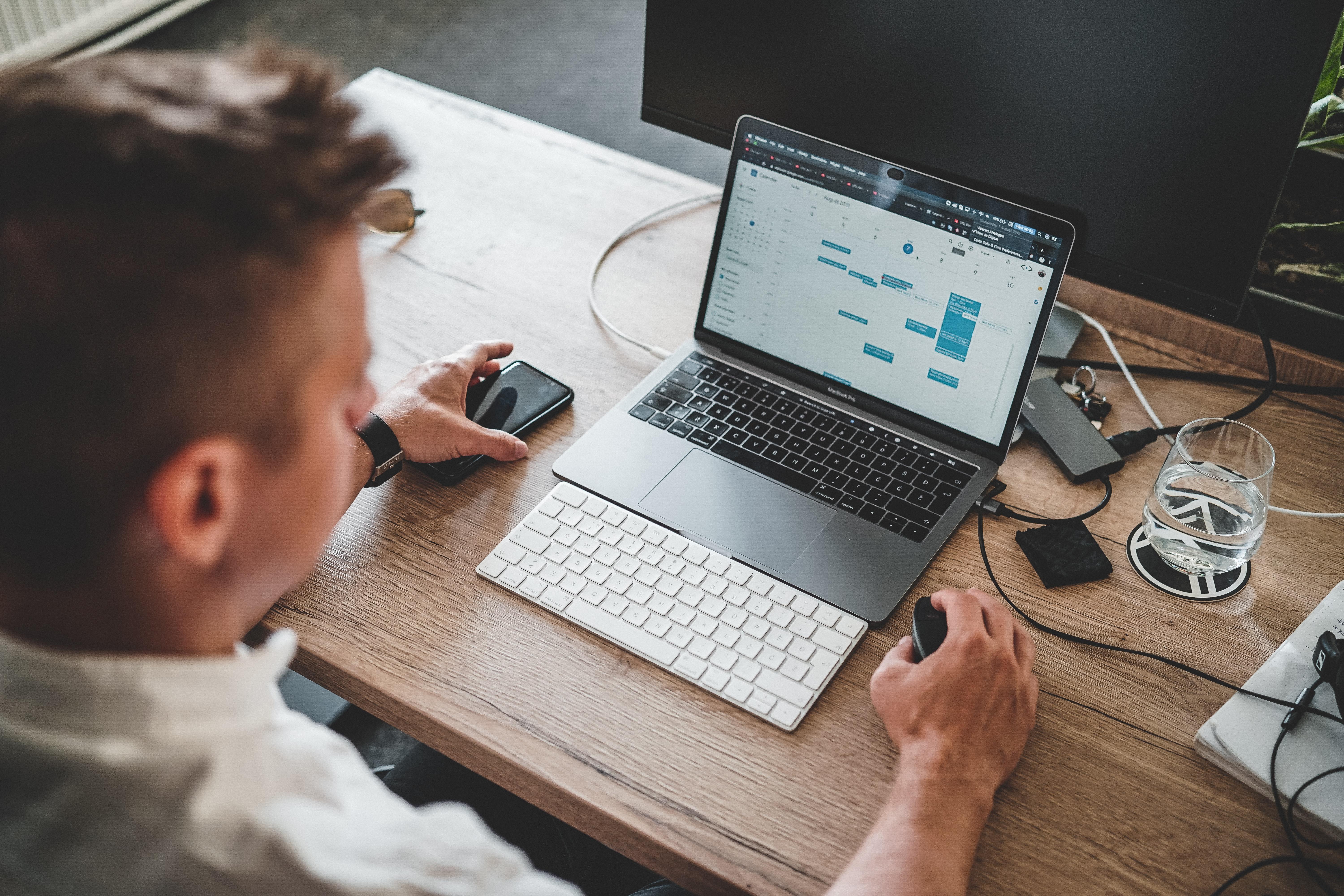 man sitting with a macbook planning his schedule