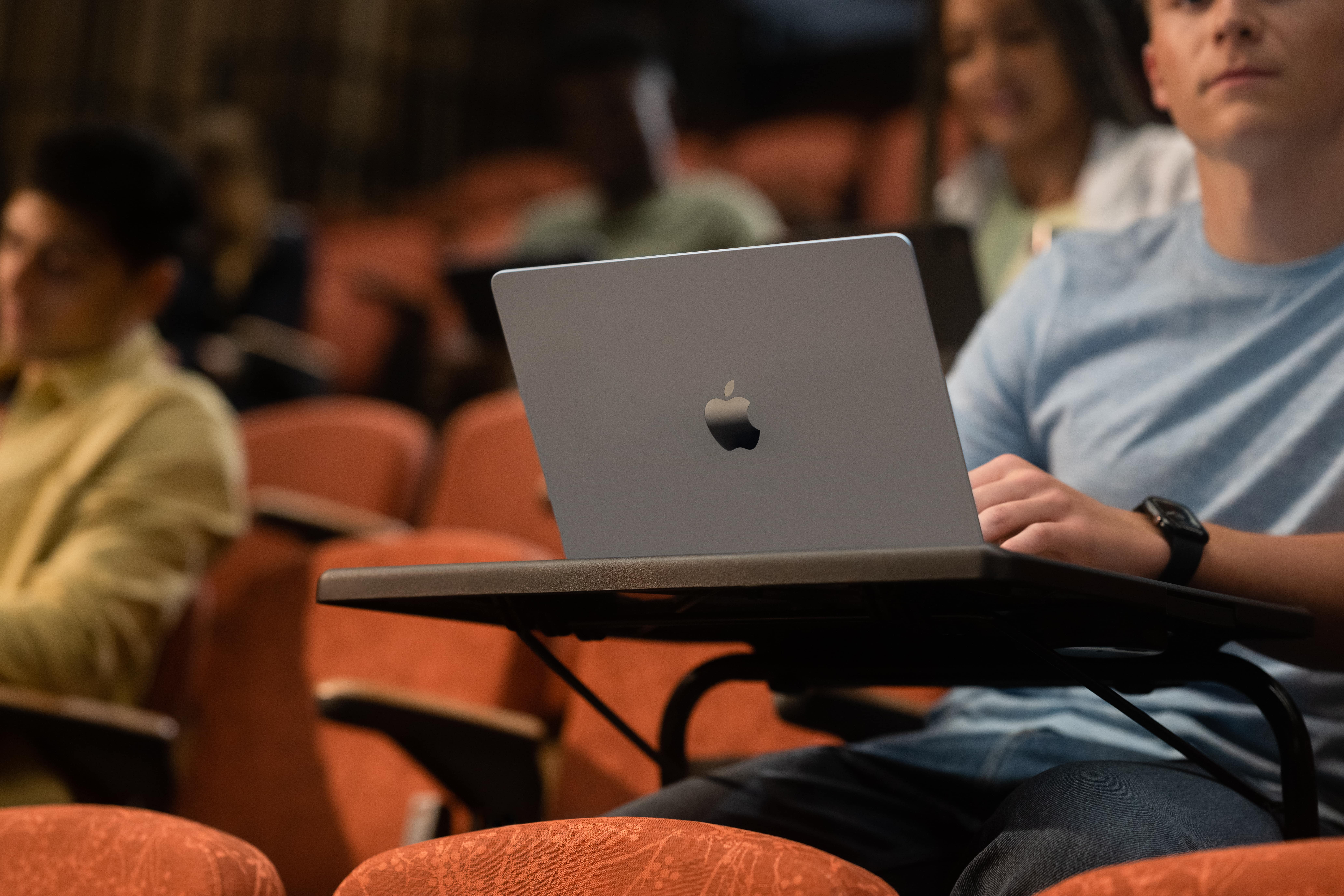 student sitting with a macbook