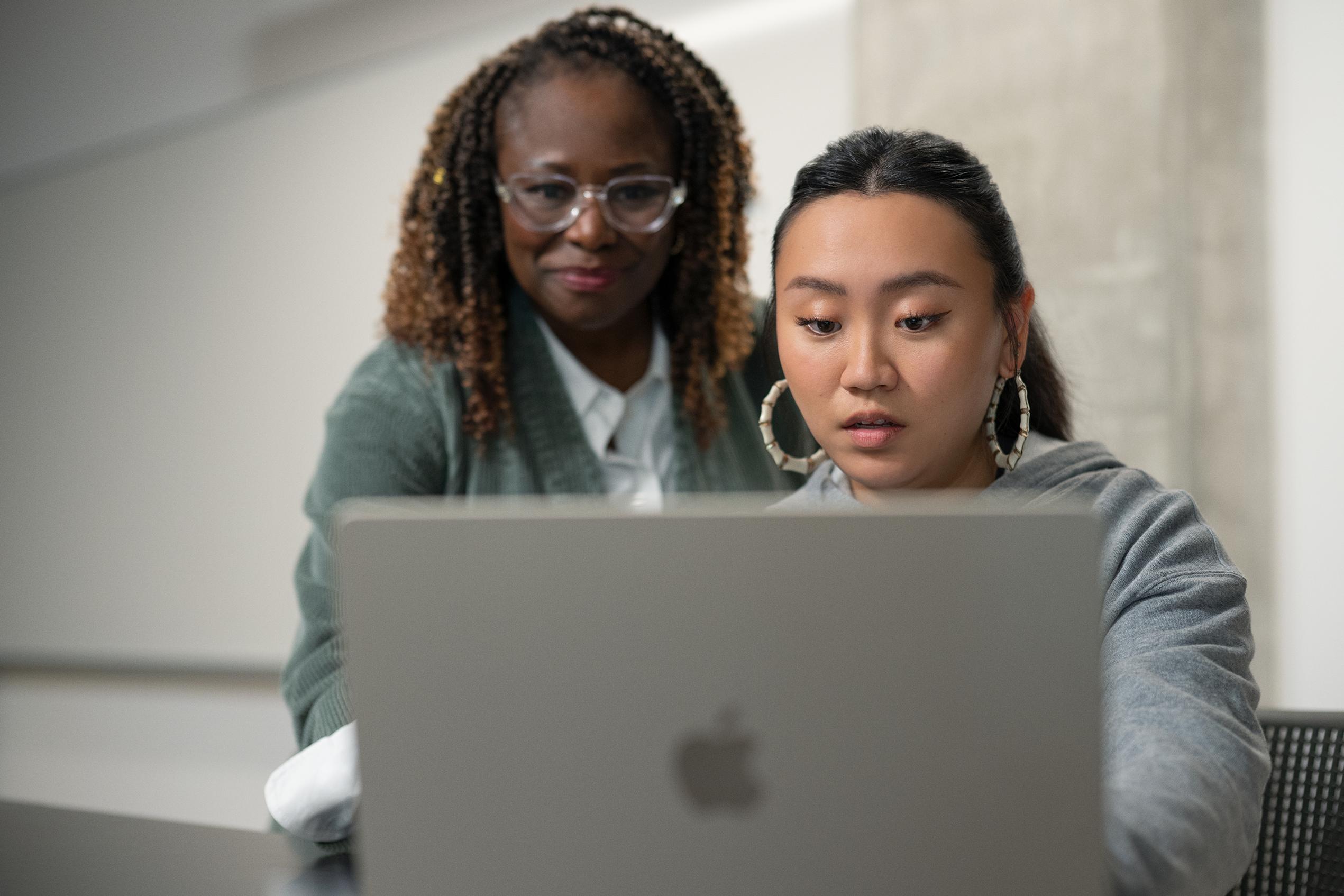 two women using a macbook