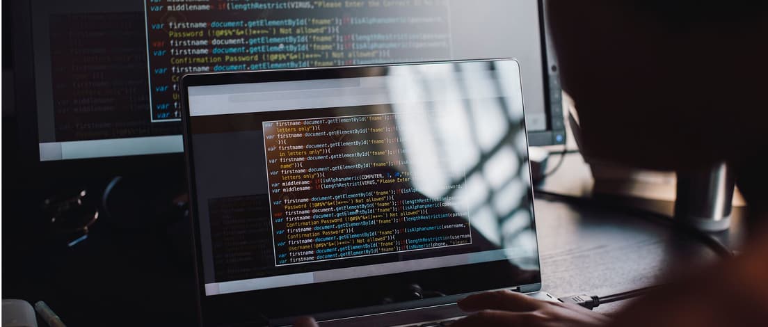 Bærbar computer og ekstern skærm, der viser programmeringskode, hvilket illustrerer et typisk setup til kodning for udviklere.