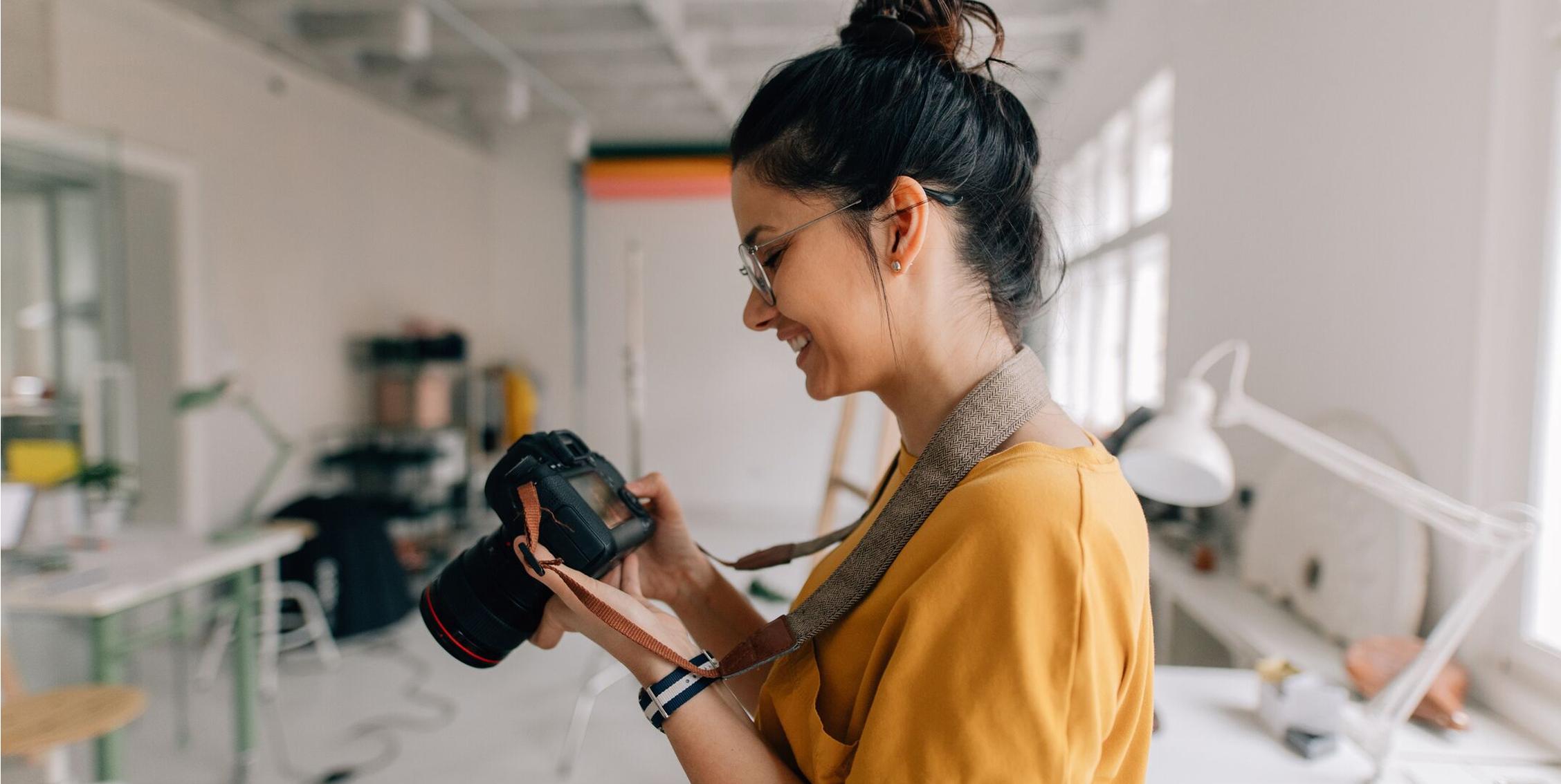 Fotograf, der gennemser billeder på et kamera i et studie, hvilket illustrerer en typisk arbejdsgang for billedredigering.