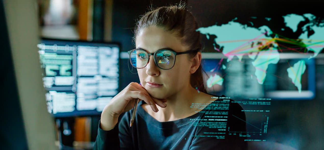 Programmører, der arbejder med en opsætning med flere skærme, hvilket illustrerer nøglefaktorer som skærmstørrelse, opløsning og ergonomi i forbindelse med programmering.