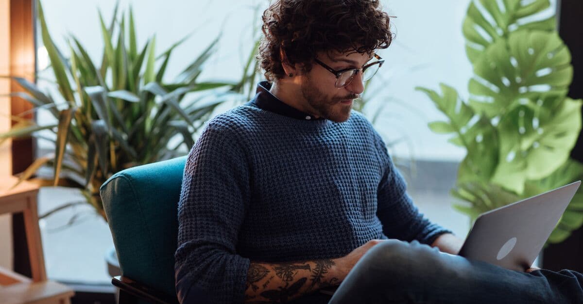 En mann sitter på et kontor og jobber på laptopen sin